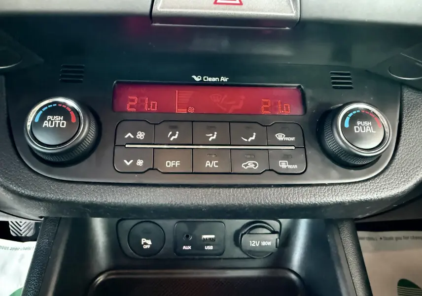 Vue rapprochée du tableau de bord du Kia Sportage 2015 montrant la climatisation automatique avec affichage digital rouge.