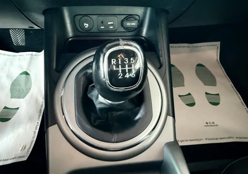 Le levier de vitesses manuel noir du Kia Sportage 2015 vu de dessus avec ports USB et prise 12V.