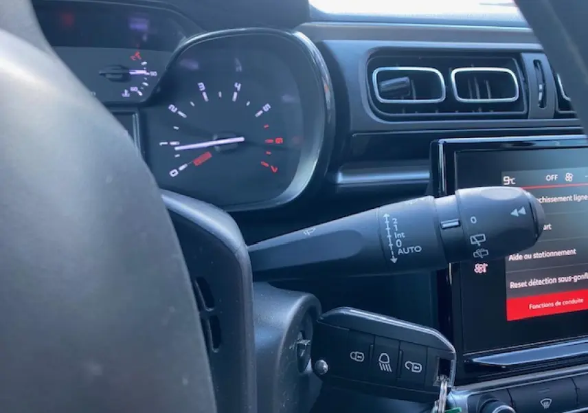 Vue rapprochée du tableau de bord et volant d'une Citroën C3 2023 noire, affichage digital et commandes visibles.