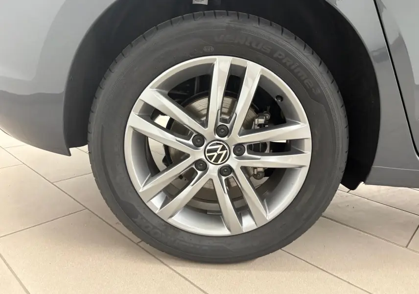 Gros plan sur la roue arrière droite du Volkswagen Touran gris Dauphin, mettant en valeur la jante alliage 17 pouces et le logo VW central.