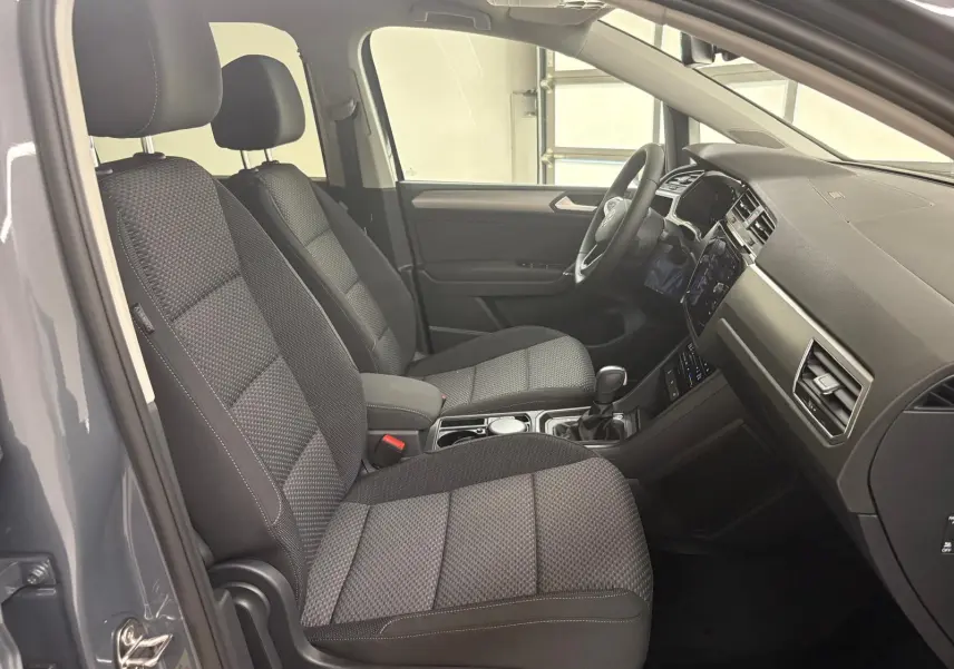 Intérieur du Volkswagen Touran 2025 gris dauphin, vue côté gauche montrant sièges avant et tableau de bord moderne.