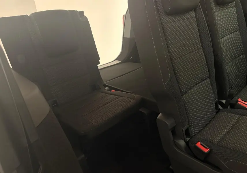 Vue intérieure sur les sièges arrière en tissu noir du Volkswagen Touran 2025, mettant en valeur la troisième rangée rabattable.