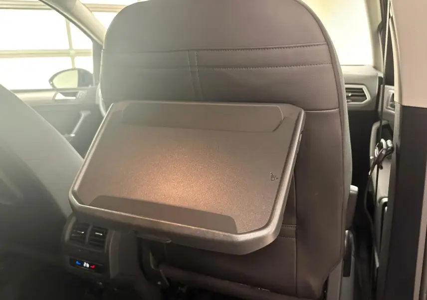 Tablette rabattable en plastique fixée au dossier du siège avant dans l'habitacle du Volkswagen Touran gris dauphin 2025.
