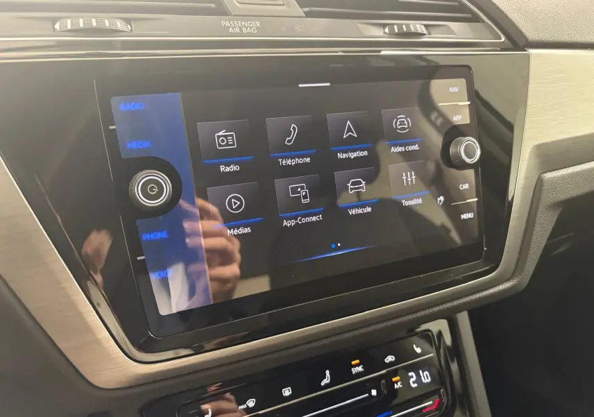 Écran tactile central du tableau de bord du Volkswagen Touran 2025 gris dauphin, affichant le menu multimédia et aides à la conduite.