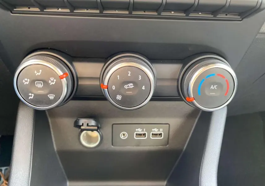 Gros plan sur les commandes de climatisation manuelle noire avec anneaux chromés et ports USB de la Renault Clio 1.5 Blue dCi noire.