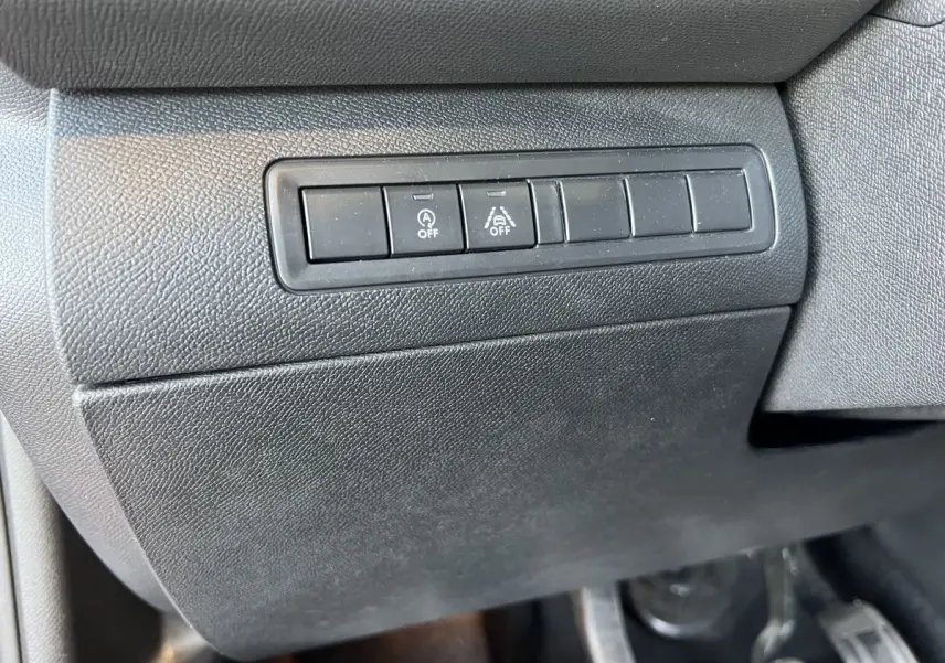 Gros plan sur les boutons de désactivation du système start-stop et de l'aide au maintien de voie dans une Peugeot 308 GT Line rouge de 2019.