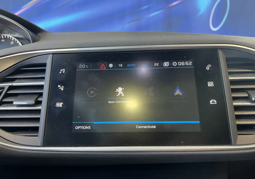 Écran tactile central affichant les applications connectées dans l'habitacle d'une Peugeot 308 rouge de 2019.