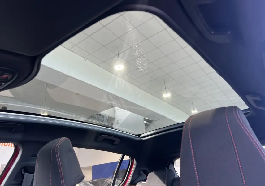 Vue intérieure du toit panoramique et des sièges avant avec surpiqûres rouges d'une Peugeot 308 rouge Puretech 130 S&S GT Line 2019