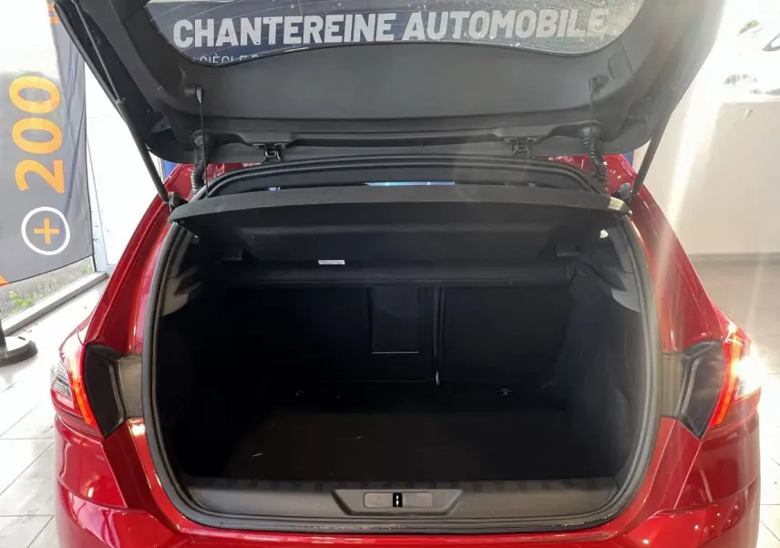 Coffre ouvert d'une Peugeot 308 Puretech 130 S&S GT Line rouge vue de l'arrière en intérieur showroom.