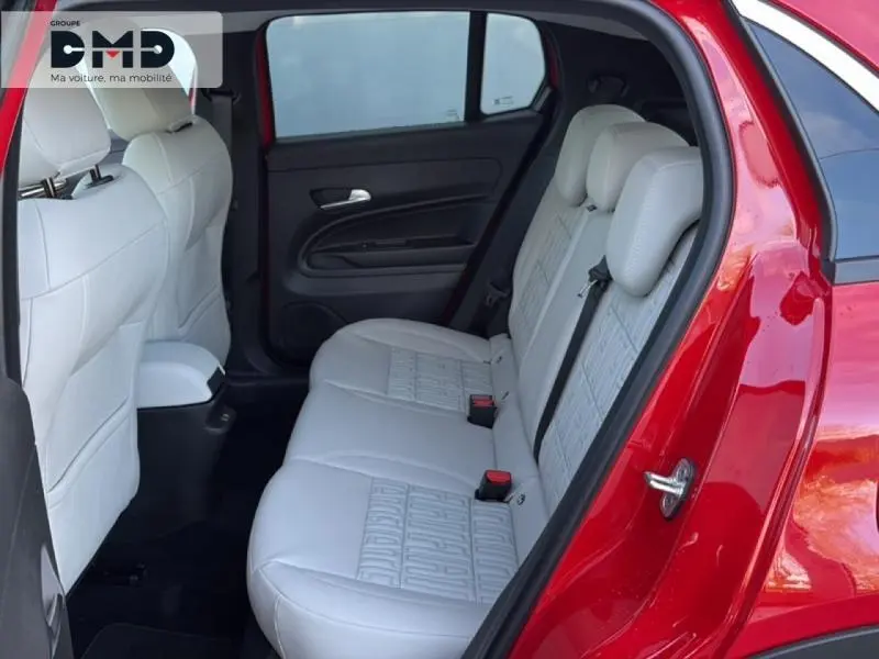 Vue côté droit sur l'intérieur arrière d'une FIAT 600 rouge avec banquette claire et détails texturés sur les sièges.