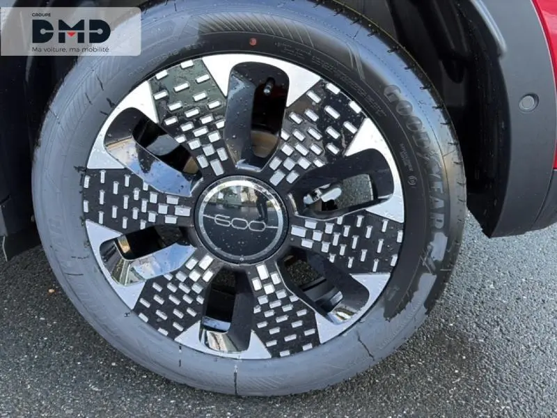 Gros plan sur la roue avant droite d'une FIAT 600 rouge, mettant en valeur la jante alu noire et argentée au design moderne.