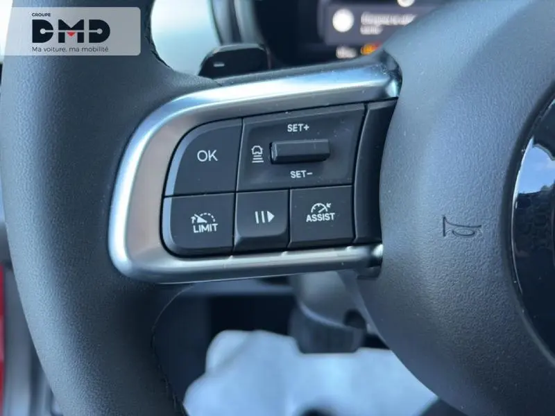 Gros plan sur les commandes multifonctions à gauche du volant d'une FIAT 600 rouge, version hybride 2026.