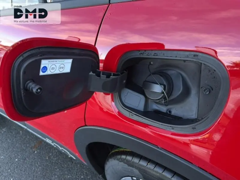 Gros plan sur la trappe de carburant ouverte côté gauche d'une FIAT 600 rouge brillante, avec bouchon essence visible.
