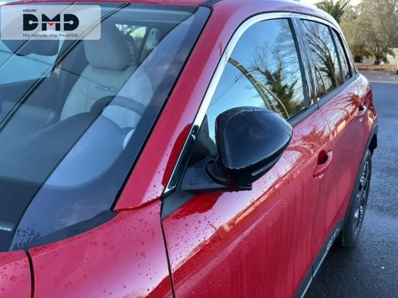 Vue côté droit avant d'une FIAT 600 rouge avec rétroviseur noir et pluie sur la carrosserie.