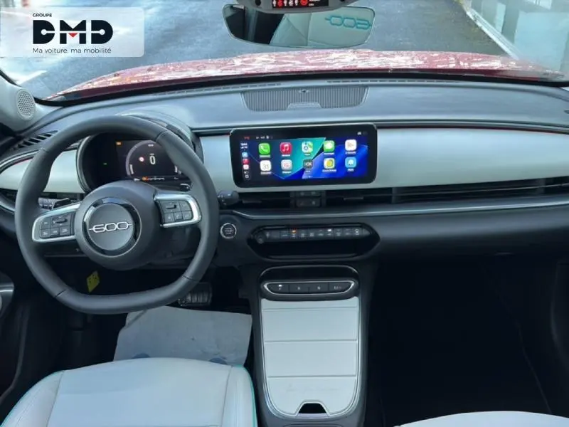 Vue intérieure avant du tableau de bord et volant noir de la FIAT 600 rouge avec écran tactile central lumineux.