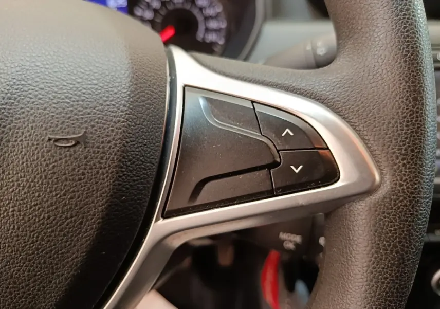 Gros plan sur les commandes du volant cuir synthétique du Dacia Duster 2021, boutons de réglage multifonctions visibles.