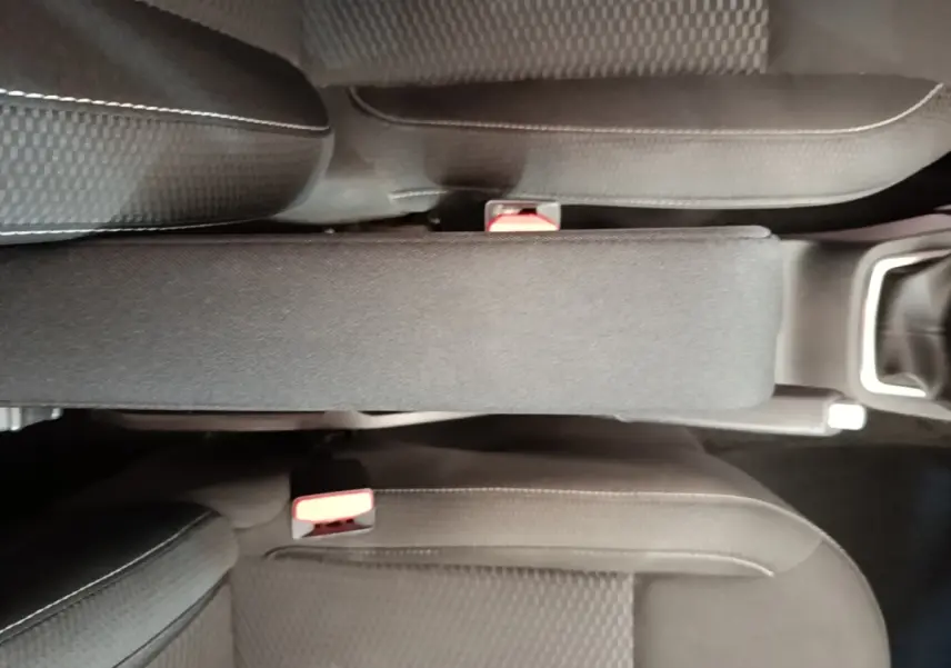 Vue plongeante sur l'accoudoir central et les sièges noirs du Dacia Duster Confort Blue dCi 115 4x4 2021.