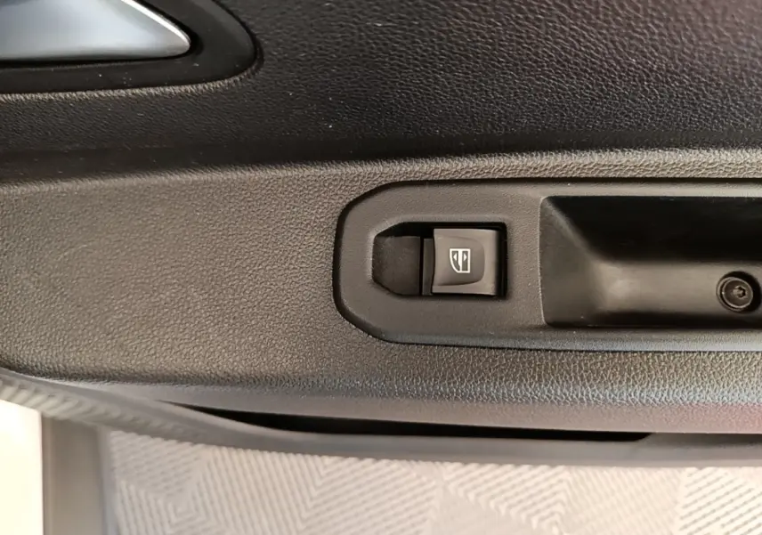 Gros plan sur le bouton de commande de la vitre électrique côté conducteur du Dacia Duster blanc, intérieur noir.