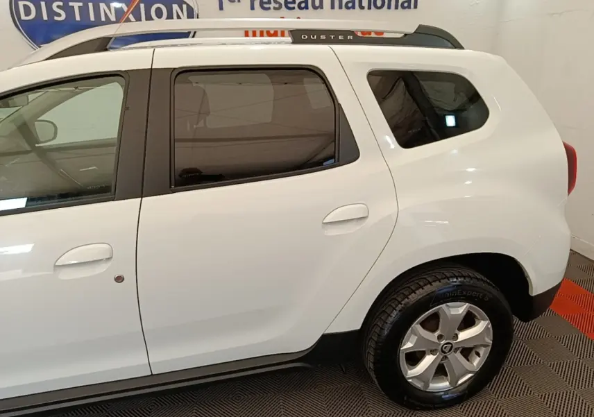 Vue latérale droite d'un Dacia Duster blanc 2021 avec vitres teintées et jantes alliage.