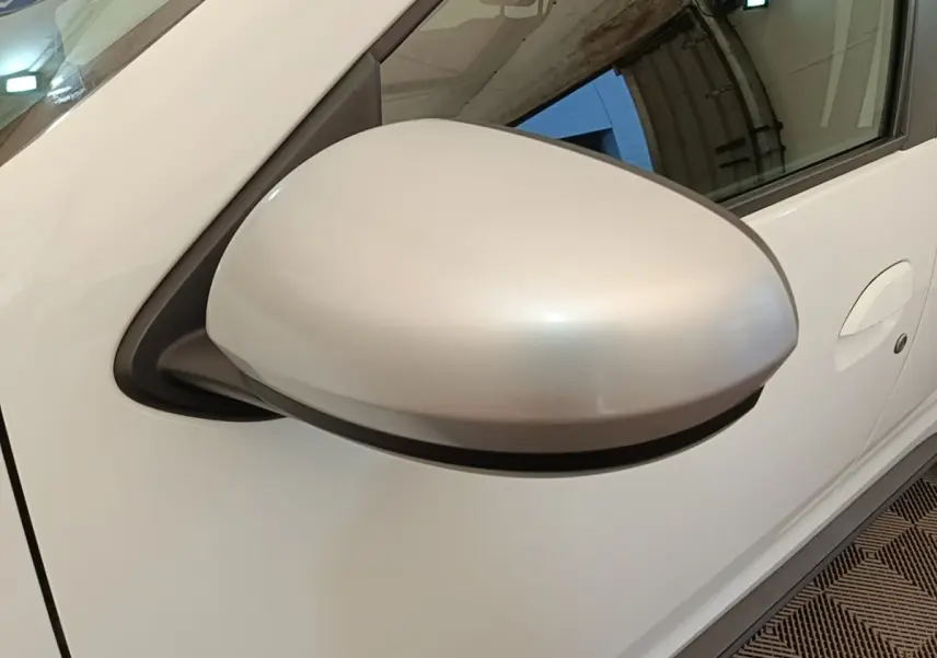 Gros plan sur le rétroviseur côté conducteur blanc du Dacia Duster Confort Blue dCi 115 4x4 blanc, vue latérale droite.