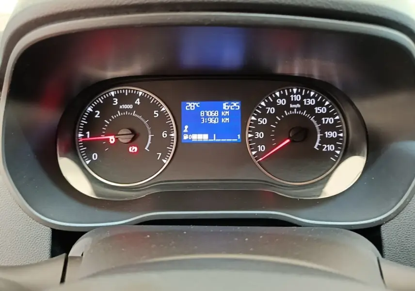 Vue rapprochée du tableau de bord du Dacia Duster blanc 2021, affichage digital et compte-tours analogiques.