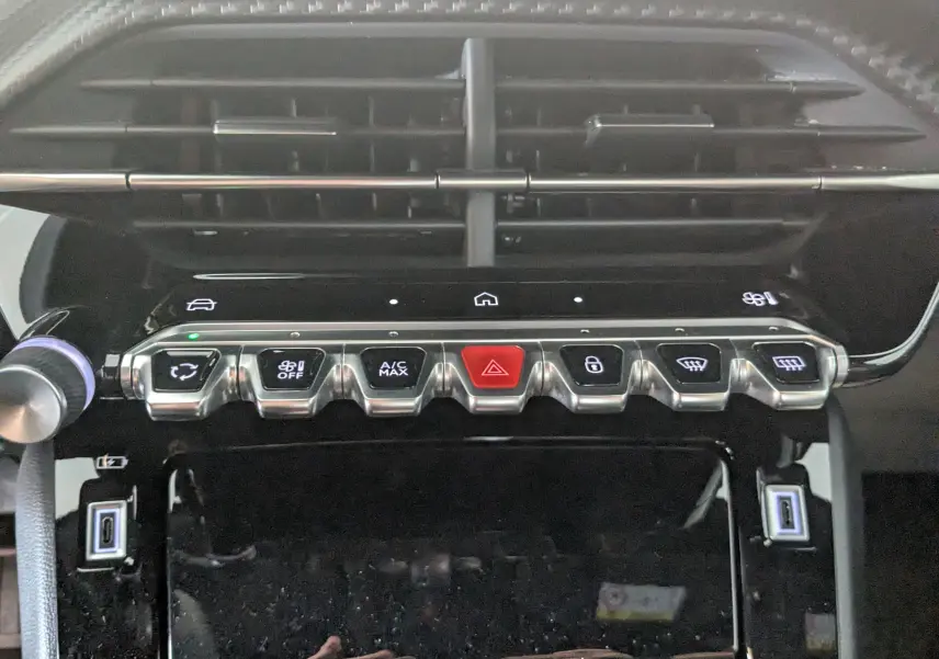 Gros plan sur la rangée de commandes chromées et boutons tactiles du tableau de bord du Peugeot 2008 Hybrid 145.