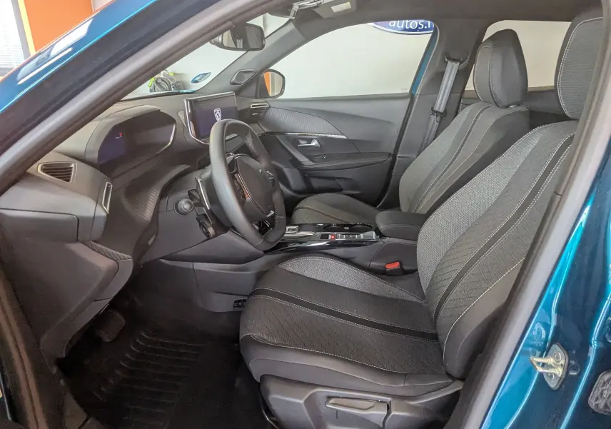 Vue intérieure côté conducteur du Peugeot 2008 Hybrid 145 bleu obsession, avec sièges tissu gris et tableau de bord moderne.