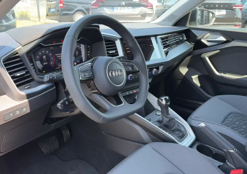 Intérieur Audi A1 Sportback 30 TFSI 2026 vu côté conducteur, tableau de bord moderne et volant cuir multifonction.