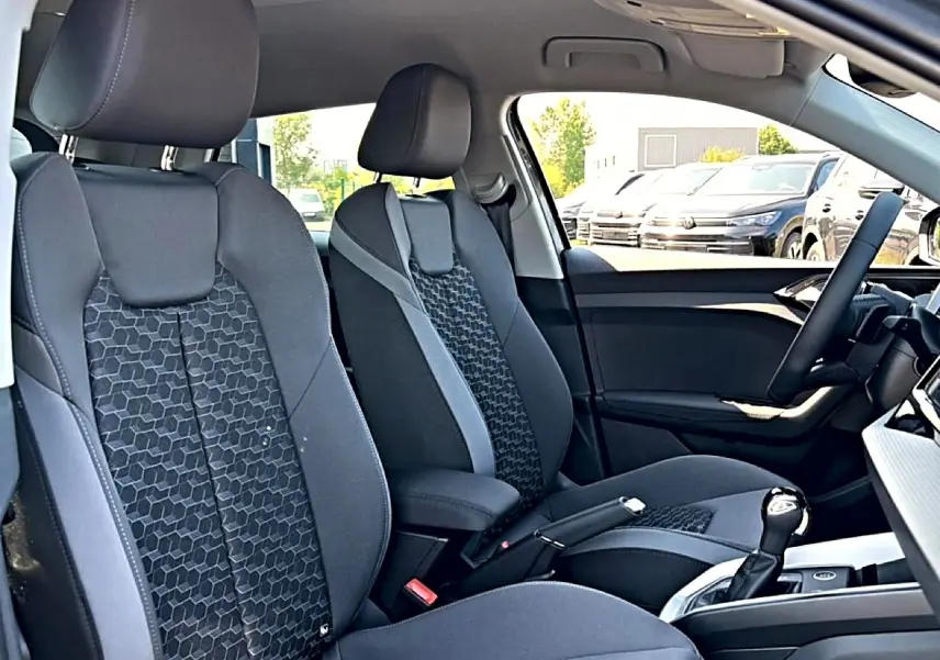 Vue intérieure côté droit de l'Audi A1 Sportback 2026 avec sièges sport noirs à motif hexagonal et accoudoir central.