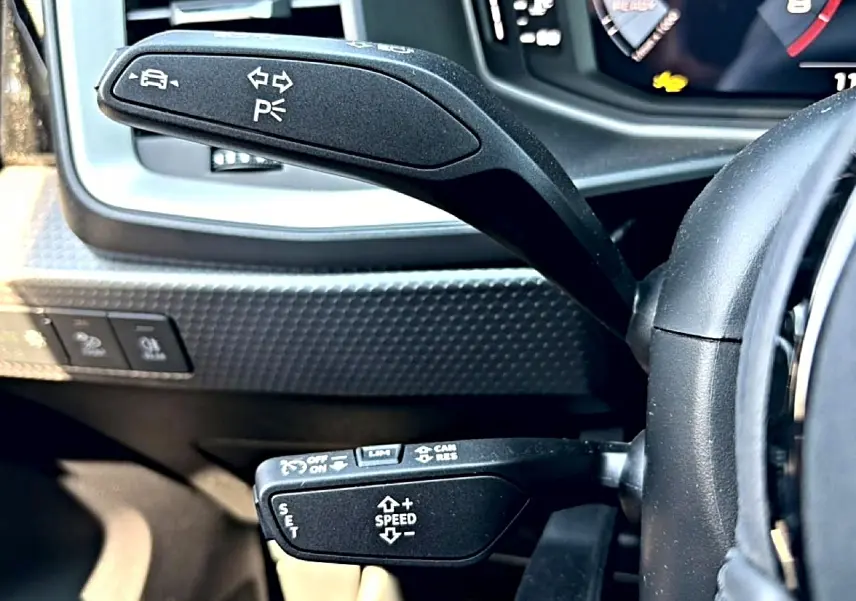 Gros plan sur les commandes au volant d'une Audi A1 Sportback 2026, avec leviers noirs et tableau de bord numérique.