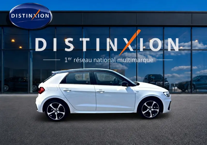 Audi A1 Sportback blanc toit noir en profil droit devant une vitrine Distinxion, avec jantes alliage noires et blanches.