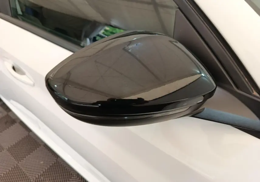 Gros plan sur le rétroviseur noir côté gauche d'une Peugeot 208 blanche, version 1.5 BlueHDi 2023.