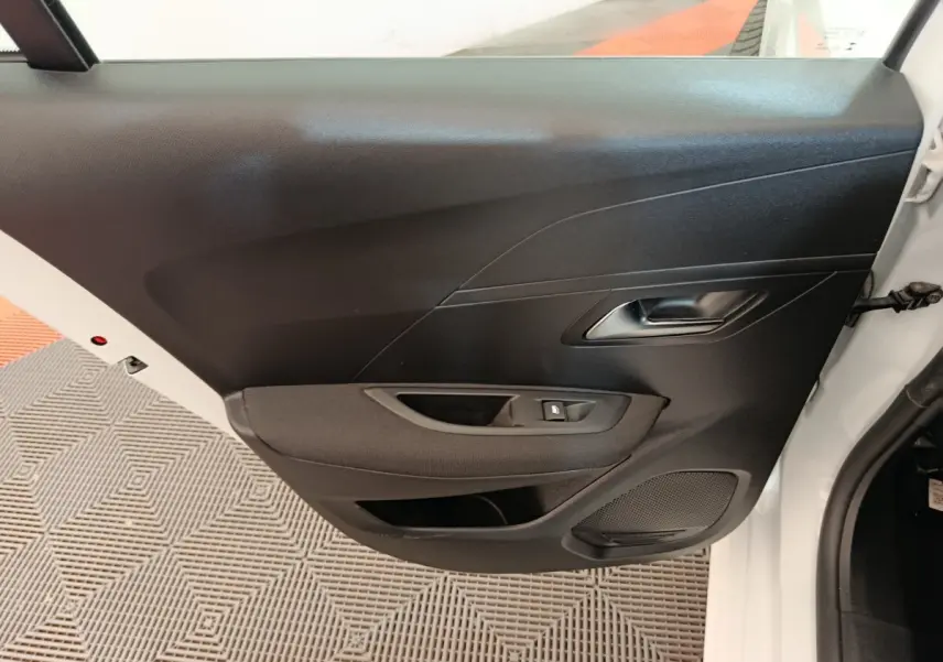 Vue intérieure de la porte avant gauche noire du Peugeot 208 blanc, avec poignée et commande de lève-vitre.