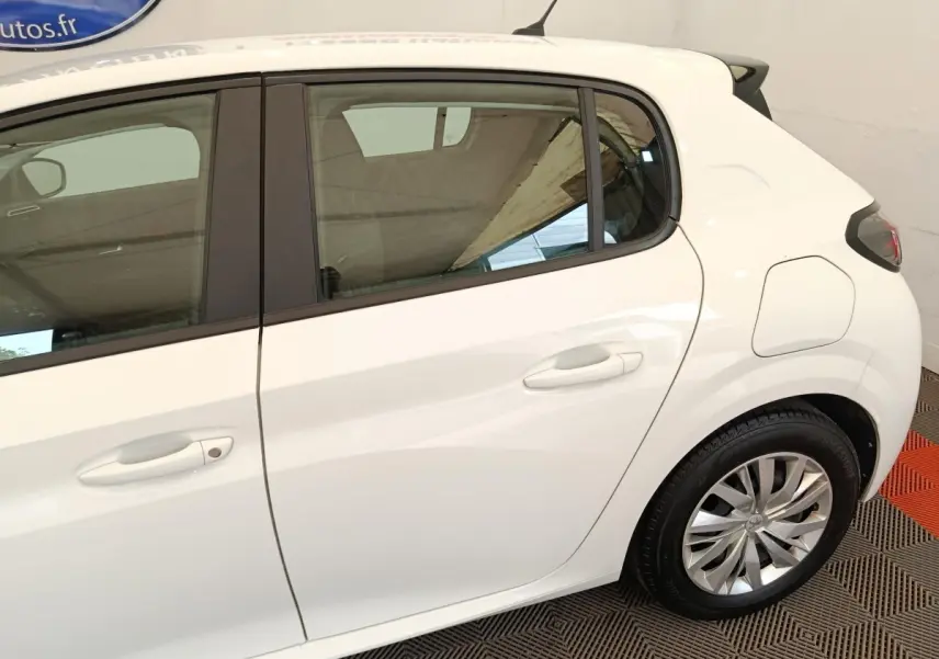 Vue latérale droite sur la partie arrière d’une Peugeot 208 blanche, avec jante alliage et porte essence visible.