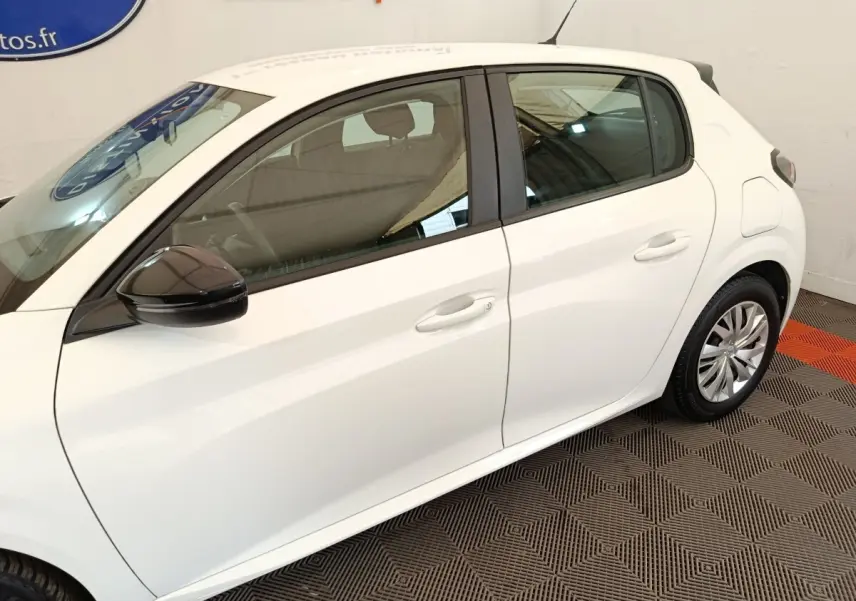 Vue latérale côté gauche d'une Peugeot 208 blanche 2023 avec rétroviseur noir et jantes acier.