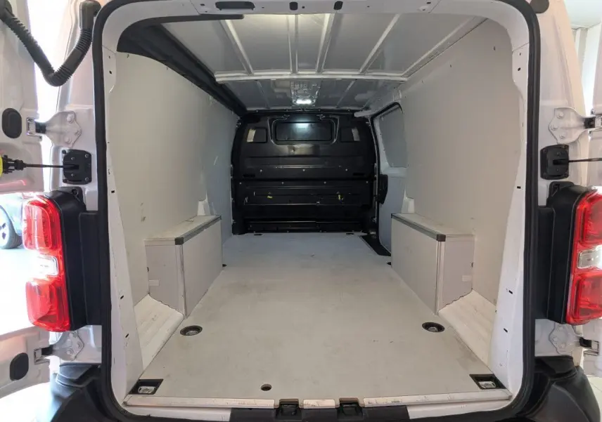 Vue arrière ouverte du fourgon FIAT Scudo XL blanc, montrant l'espace de chargement vide et les parois intérieures claires.