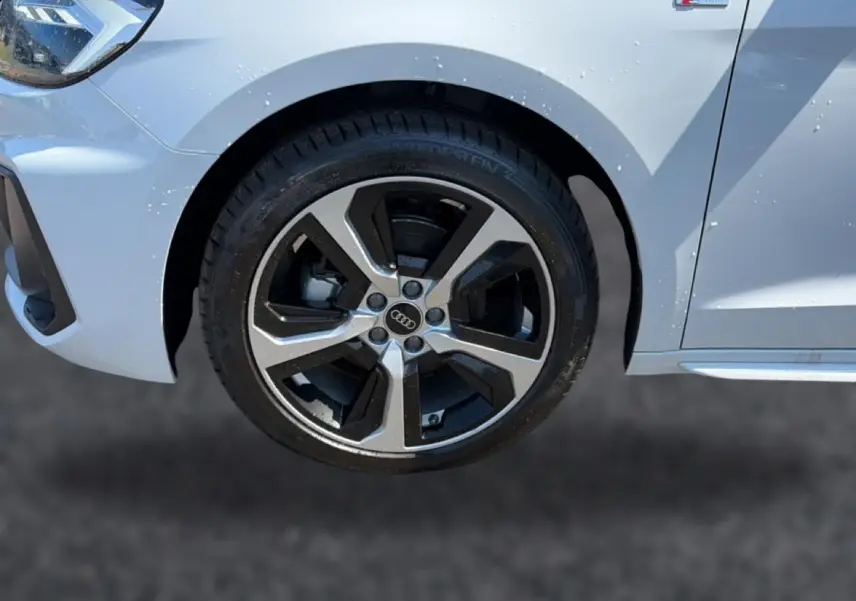 Gros plan sur la roue avant gauche et l’aile blanche d’une Audi A1 Sportback 30 TFSI S line 2026 avec jante alu bicolore.