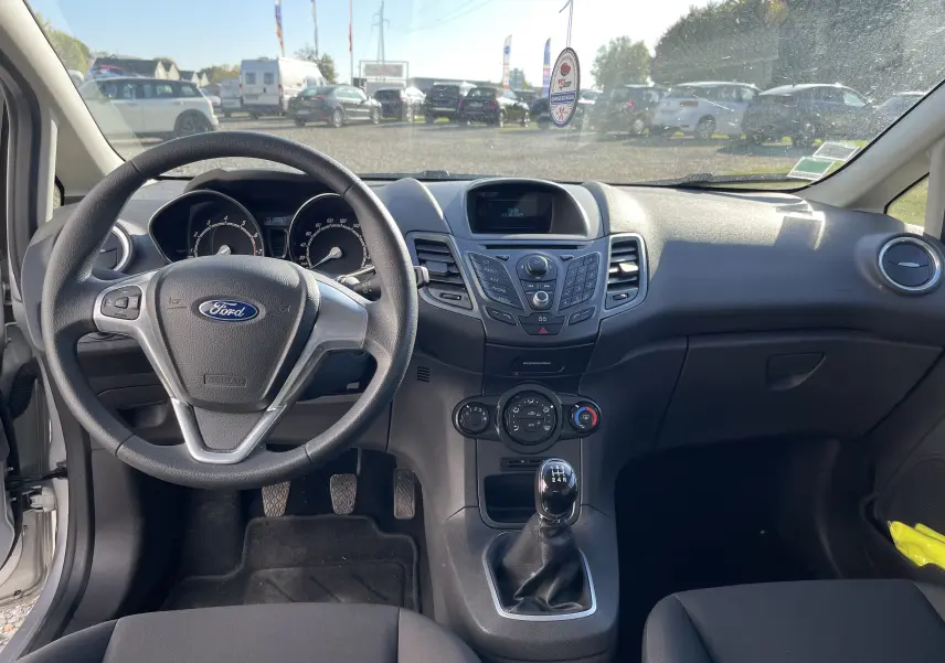 Intérieur de la Ford Fiesta 2014 gris titane, vue du poste de conduite avec volant, tableau de bord et levier de vitesse manuel.