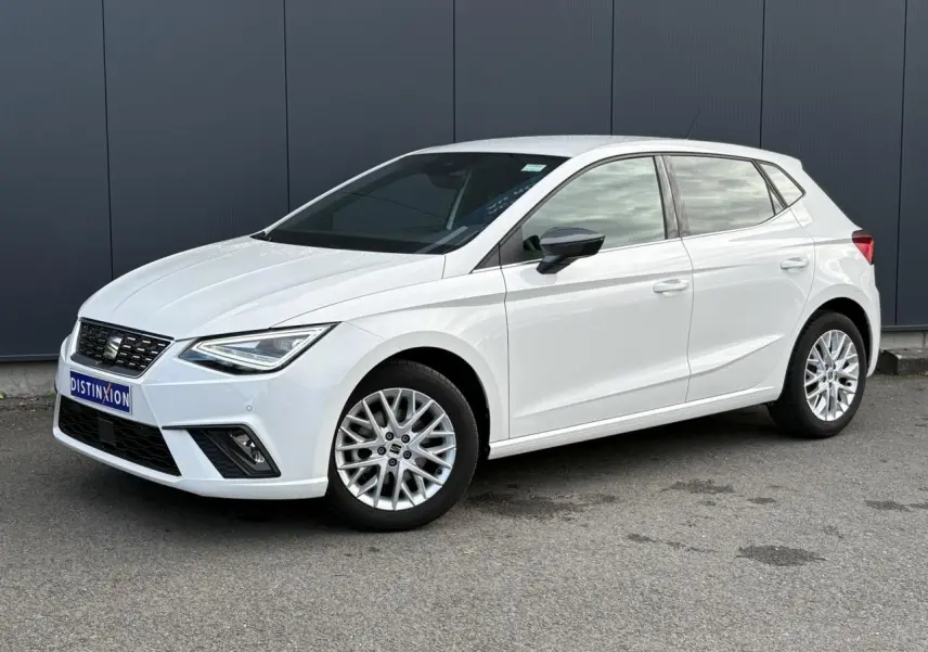 SEAT Ibiza TSI 115 Xcellence blanc vue 3/4 avant avec jantes alliage et rétroviseurs noirs sur fond urbain.