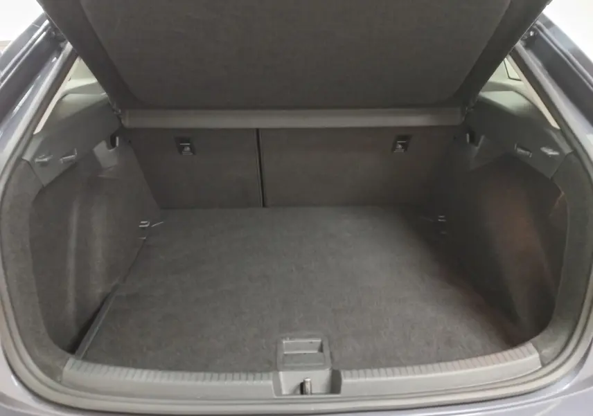 Coffre ouvert vu de l'arrière d'un Volkswagen Taigo gris cendré, montrant un espace de chargement vide et propre.
