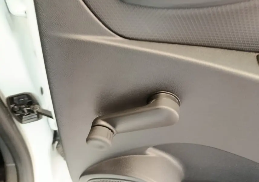 Poignée de manivelle de vitre côté gauche sur porte intérieure noire d’une Renault Clio blanche 2018.