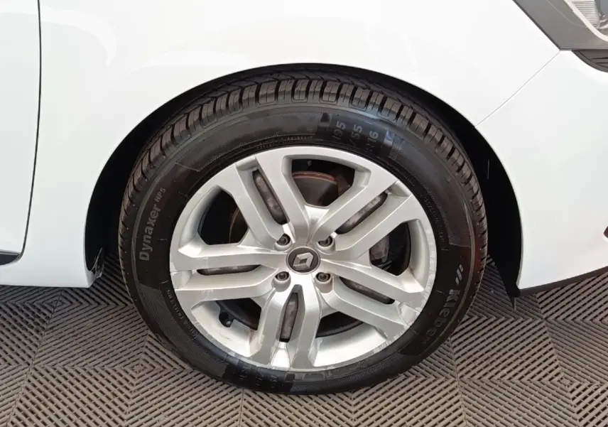 Gros plan sur la roue avant droite d’une Renault Clio blanche, avec jante alliage et logo Renault central.