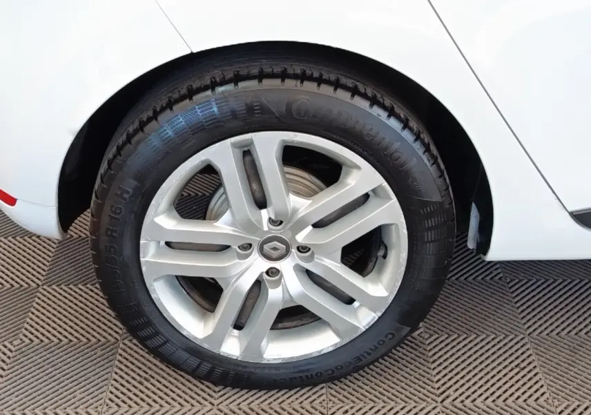 Gros plan sur la roue arrière droite blanche d’une Renault Clio Business dCi 75 avec jante alliage argentée.