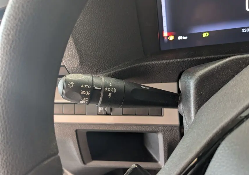 Gros plan sur le commodo d'éclairage à gauche du volant dans l'habitacle du Fiat Scudo Fourgon blanc 2025.