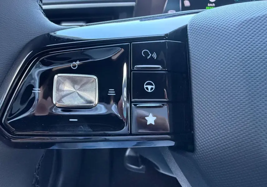 Gros plan sur les commandes multifonctions noires du volant côté gauche du MG3 Pebble Black métallisé 2026.