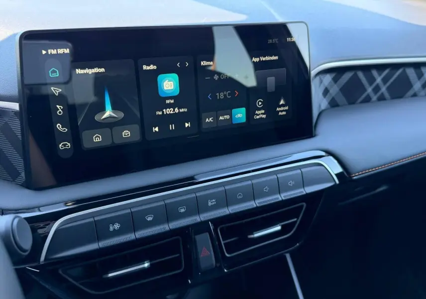Vue rapprochée de la console centrale du MG3 1.5 Hybrid+ 2026 avec écran tactile et commandes climatisation, finition noire.