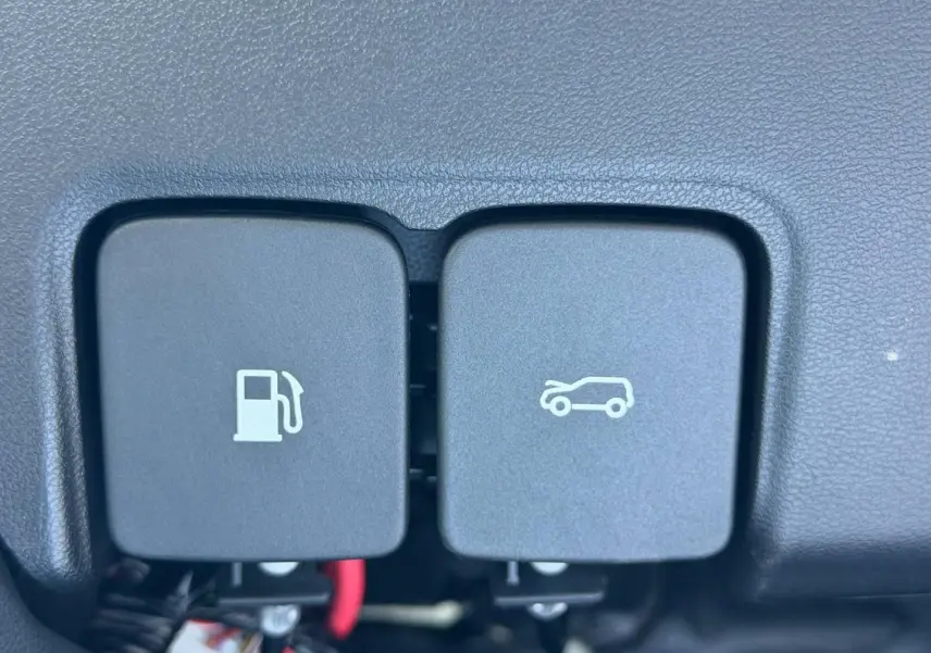 Gros plan sur les boutons d'ouverture de trappe à carburant et de coffre dans l'habitacle du MG3 Pebble Black.