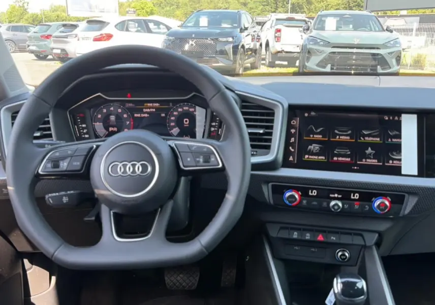 Vue intérieure centrée sur le volant multifonction Audi et le tableau de bord numérique d'une A1 Sportback 2026.