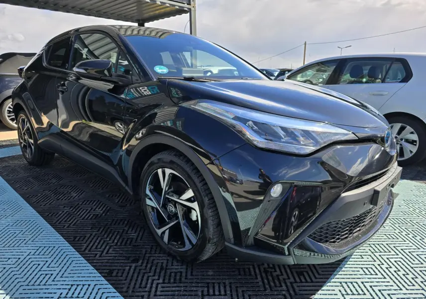 Toyota C-HR noir métal vu en 3/4 avant droit, avec jantes alliage 18 pouces et optiques LED distinctives.