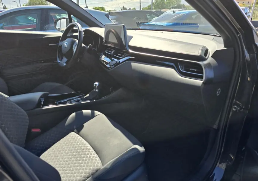 Intérieur côté passager du Toyota C-HR noir métal 2023, avec tableau de bord moderne et sièges tissu/cuir embossés.